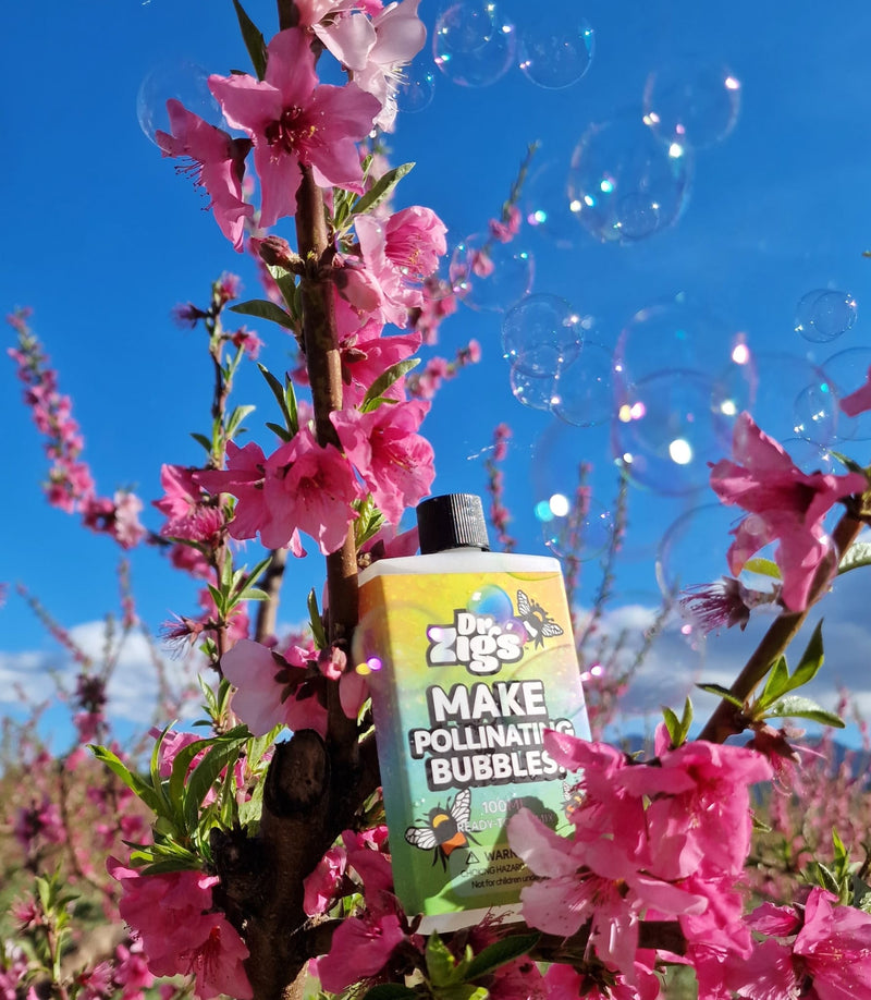 Bubble Pollination Kit by Dr Zigs non toxic mix vegan.  Bottle of Pollinating Mix resting on the branches of cherry tree with blue skies and Bubbles containing pollen floating in the background