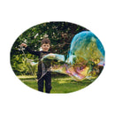 Boy outdoors making a very large iridescent bubble with giant bubble wands