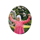 Child in a pink dress holding Dr Zigs wooden bubble wands and making a giant bubble outdoors